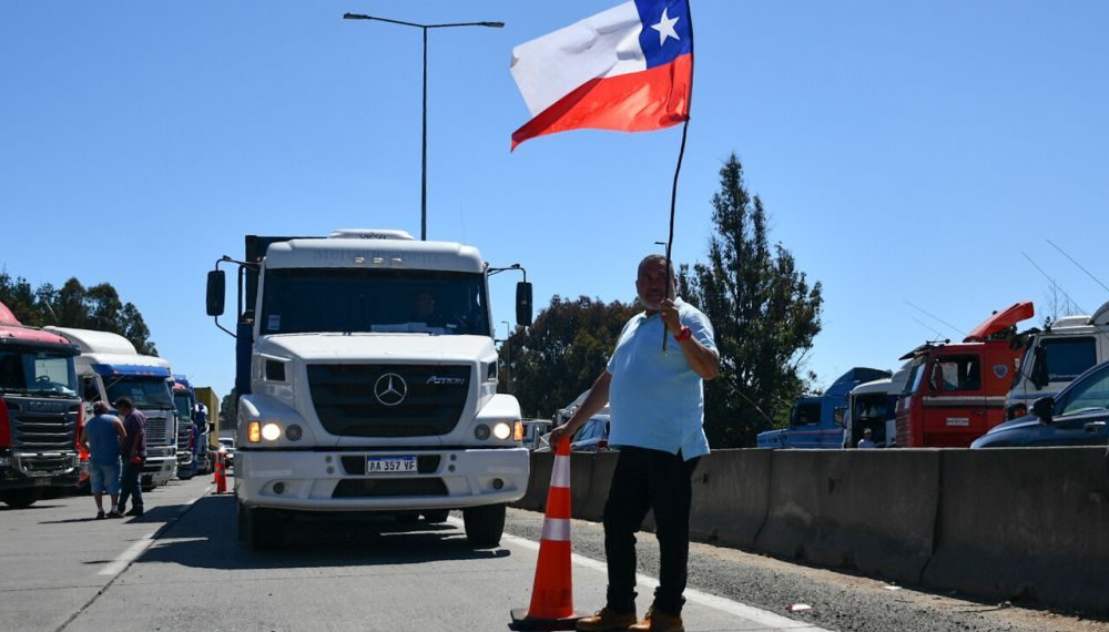 Camionero bloqueando completamente la Ruta 68, sosteniendo una bandera chilena