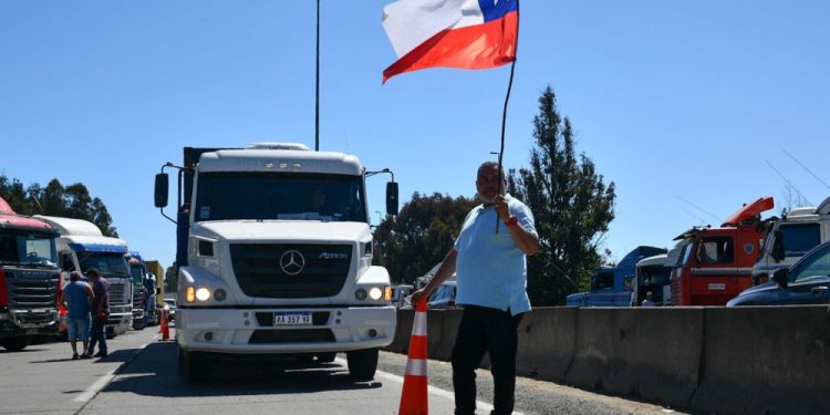 Camionero bloqueando completamente la Ruta 68, sosteniendo una bandera chilena